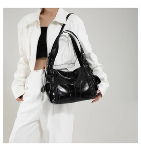 Close-up of black glossy PU leather handbag with multiple functional zipper pockets