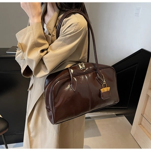 Detail of dark brown glossy PU leather Boston bag with gold zipper and dual handles