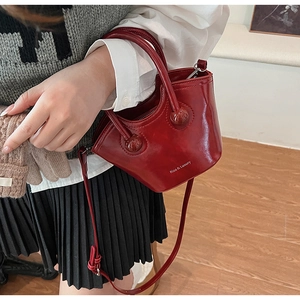 Detail showing red glossy patent leather bucket bag with top handle and shoulder strap