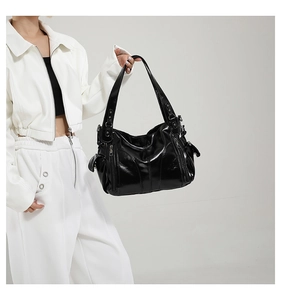 Detail of black patent leather hobo bag with multiple silver zippers and glossy texture