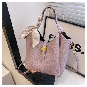 Close-up of purple lychee leather bucket bag with silk scarf handle and golden metal clasp