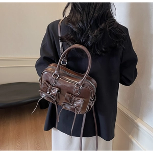 Detail of vintage brown glossy handbag featuring elegant bow ribbons and double zipper design