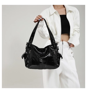 Detail of a black PU leather shoulder bag with multi-pocket design and silver hardware