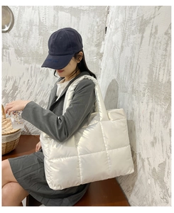 Detail showing the white quilted puffer tote bag with puffy square patterns on a model