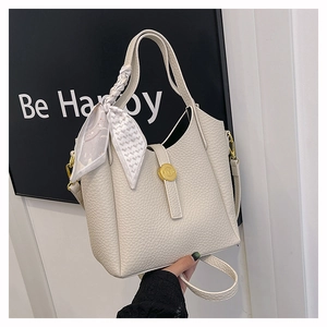 Close-up of beige lychee textured leather bucket bag with silk scarf and gold buckle
