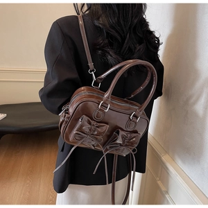 Detailed back view of a vintage brown leather backpack with bow knots and glossy finish