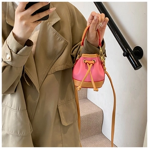 Mini sac seau rose à cordon porté par un mannequin avec bandoulière réglable