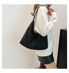 Vista laterale di una borsa hobo nera in nylon capiente indossata da una modella chic