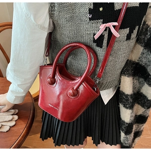 Detail of red glossy bucket bag with Rice & Luxury print and pink velvet bow accent