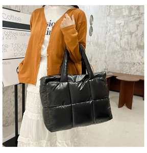 Close-up of black glossy quilted nylon tote bag featuring a padded puffy design and handle