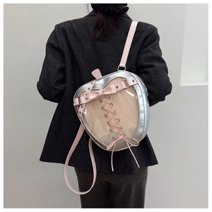 Silver apple-shaped ita bag with pink bow and transparent window shown on a model
