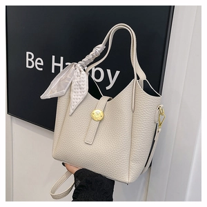 Close-up of beige leather bucket bag with silk scarf detail and golden metal lock