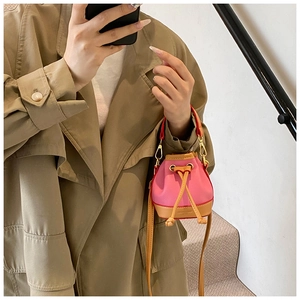 Gros plan du sac seau rose à cordon avec texture grainée et poignée rouge vive