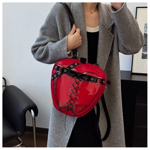 Detail of red heart-shaped ita bag featuring transparent window and black ribbon lacing