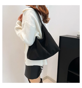 Grande borsa a spalla nera minimalista con finitura opaca indossata da modella in ambiente