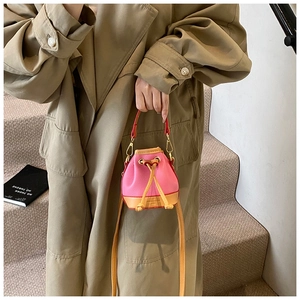 Mini sac seau avec cordon de serrage, corps rose et sangle jaune porté par un modèle