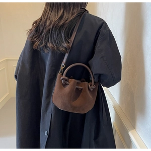 Detailed view of the brown suede bucket bag with a knot handle and detachable shoulder strap