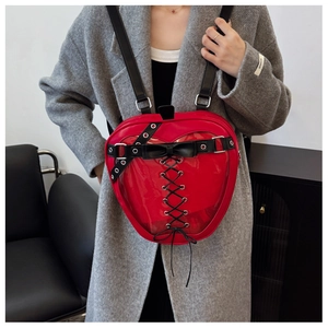 Detail view of a red apple-shaped backpack with glossy finish and black bow decoration