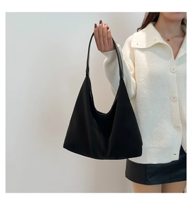 Borsa tote nera minimalista in nylon con tracolla larga indossata da una modella