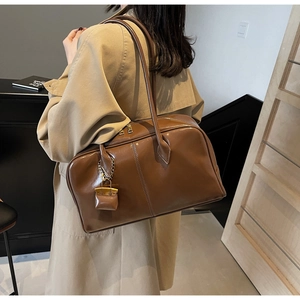 Detail of vintage dark brown faux leather Boston bag on model in khaki trench coat