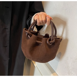 Detail of retro dark brown suede bucket bag with unique knotted leather handle design