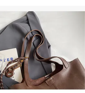 Brown leather tote bag featuring a magnetic clasp closure and a woven decorative charm