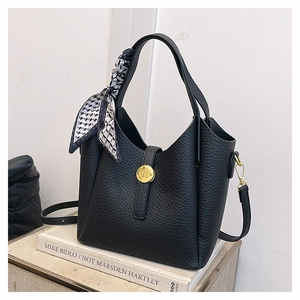 Detail of black pebbled leather bucket bag featuring a gold N-logo clasp and decorative silk scarf