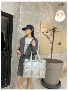 Detail shot of a silver quilted puffer tote bag with high-shine metallic finish and square padding