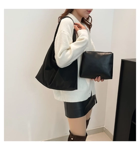 Vista dettagliata della borsa tote nera e della pochette abbinata su un modello