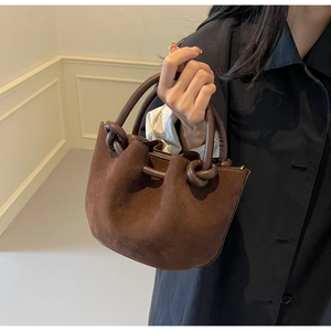 Detail of dark brown suede bucket bag featuring a unique knotted handle design