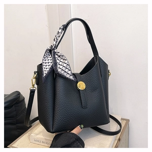 Detail of black lychee grain bucket bag with checkered scarf and gold hardware