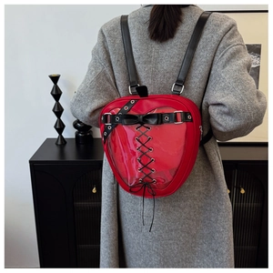 Detail of red heart-shaped ita bag with transparent PVC window and bow accents