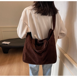 Macro detail of dark brown suede tote bag showing soft matte texture and wide shoulder strap