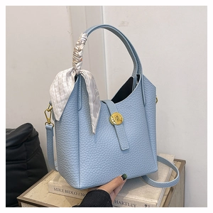 Detail of blue bucket bag with lychee texture leather, silk scarf handle, and gold buckle