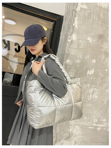 Detail of metallic silver quilted tote bag showing padded texture and wide shoulder strap