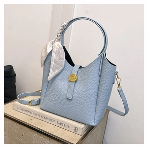 Detail of blue pebbled leather bucket bag with gold buckle and floral silk scarf accessory