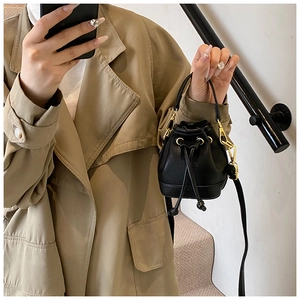 Détail du mini sac seau en cuir noir avec ferrures dorées et cordon de serrage pratique