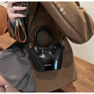 Detail shot of glossy black patent leather bucket bag with silver hardware and logo