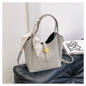 Detail view of gray lychee leather bucket bag with silk scarf and gold N-buckle
