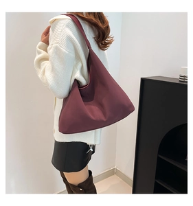 Grande borsa hobo bordeaux scuro indossata da una modella in un ambiente moderno