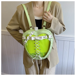 Detail view of light green apple-shaped backpack with transparent window and white bow