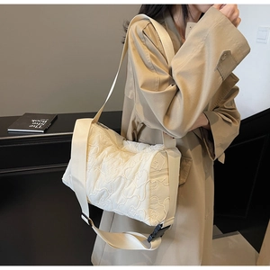 Detailed view of cream quilted shoulder bag with bear patterns and wide strap