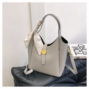 Detail view of light gray bucket bag with lychee texture, silk scarf, and gold hardware