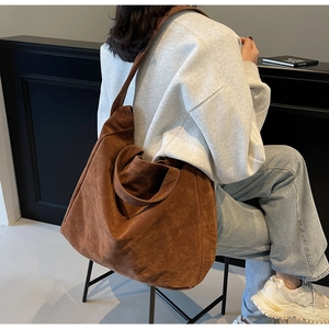 Detail of a large brown suede hobo tote bag worn with casual clothes in a modern interior