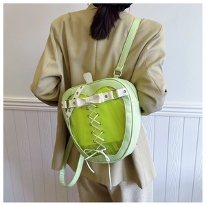 Detail view of heart-shaped green backpack featuring a clear window and lace-up bow decor
