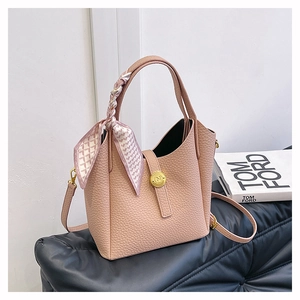 Detail of pink lychee leather bucket bag with decorative silk scarf and gold hardware