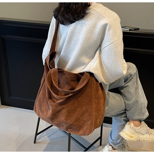 Close-up of a large brown suede tote bag featuring a minimalist design and soft texture