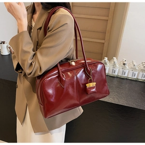 Detail of burgundy glossy leather shoulder bag with gold metal lock and long handles