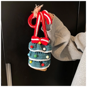 Détail d'un sac seau au crochet en forme de sapin de Noël avec pompons et nœud rouge