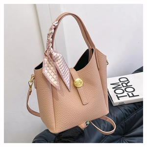 Detail view of pink lychee leather bucket bag with silk scarf handle and gold hardware